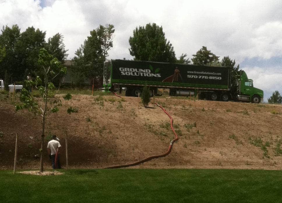 blower truck placed compost blanket with seed injected over a new park onto a slope