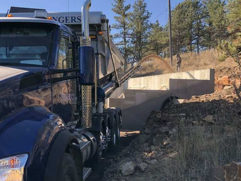 Ground Solutions and Bedrock Slingers installed a perimeter drain around and backfilled this hard-to-access foundation with 500 tons of Pea Gravel and 100 tons of topsoil