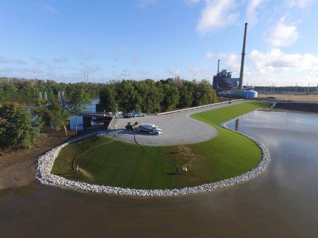 Sand infill in an artificial turf system surrounding fly ash pond using blower trucks in Illinois